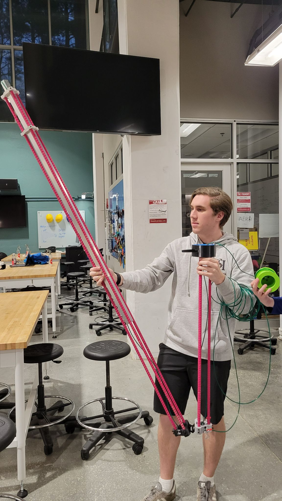 Me holding the long fiberglass rebar of testing device in an incomplete state, currently unfolding it to test the hinge.