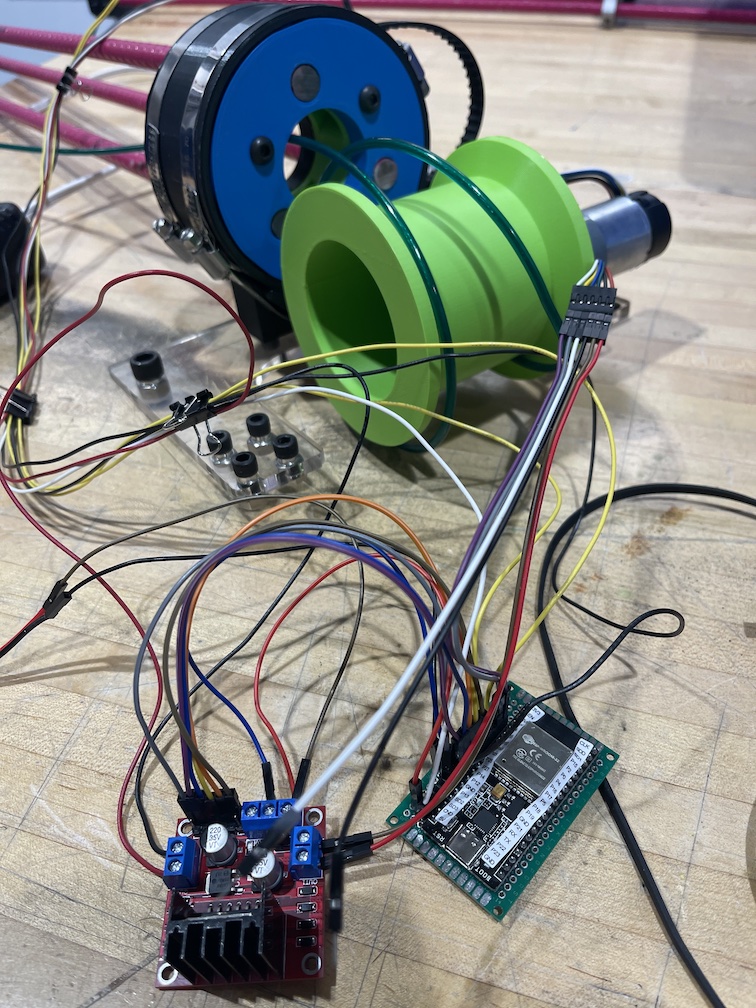 A large number of long wires connecting an H-Bridge motor driver, an ESP32 attached to a protoboard, and an early 3D-printed prototype of the rotation and depth adjustment mechanisms.