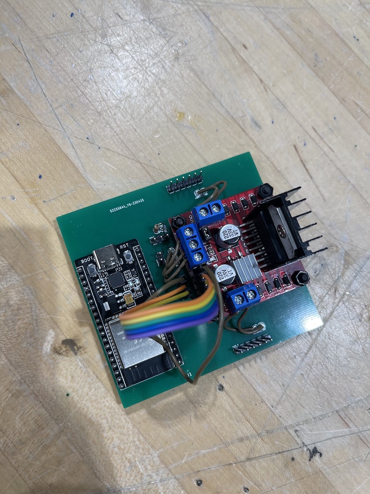 A small PCB with an ESP32 microcontroller and H-Bridge motor driver attached, along with several jumpers connecting the H-Bridge to the PCB.