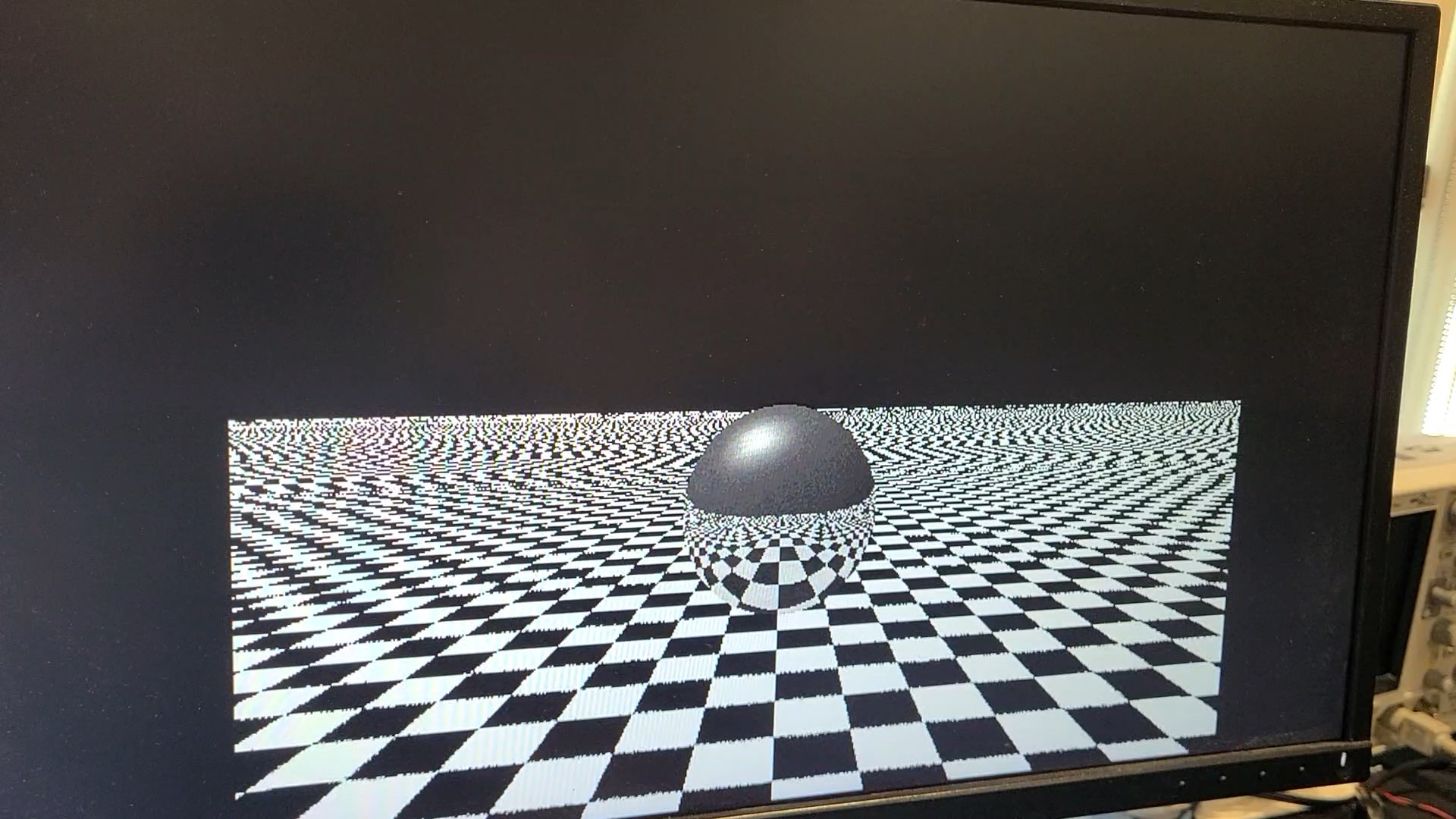 A monitor displaying a ball sitting on a checkerboard with reflections.