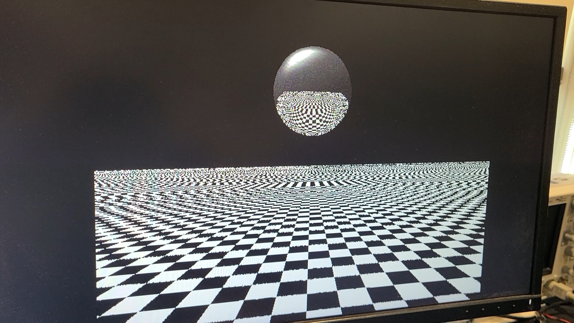 A monitor displaying a ball floating above checkerboard with reflections.