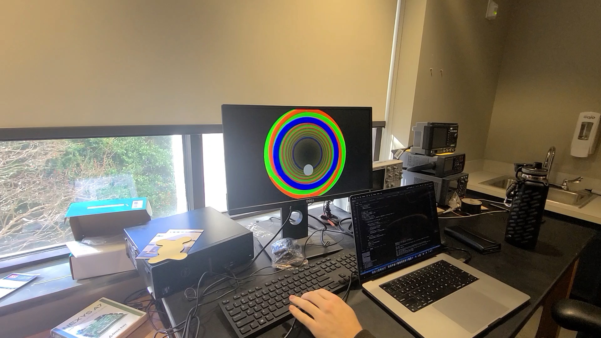 A monitor displaying a gray ball rolling through a red and green spiralled tunnel, jumping over a blue ring in the tunnel.